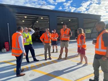 A group of people in orange vests standing in front of a building

Description automatically generated