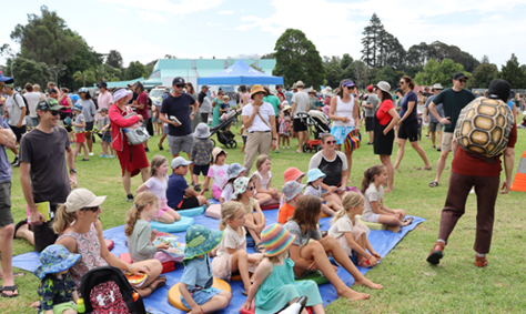 A group of people sitting on a blanket in a park

Description automatically generated