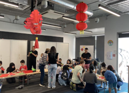 A group of people in a room with tables and red lanterns

Description automatically generated