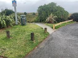 A road with a sign and bushes

Description automatically generated
