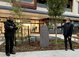 Two men standing next to a tombstone

Description automatically generated