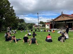 A group of people sitting on grass

Description automatically generated